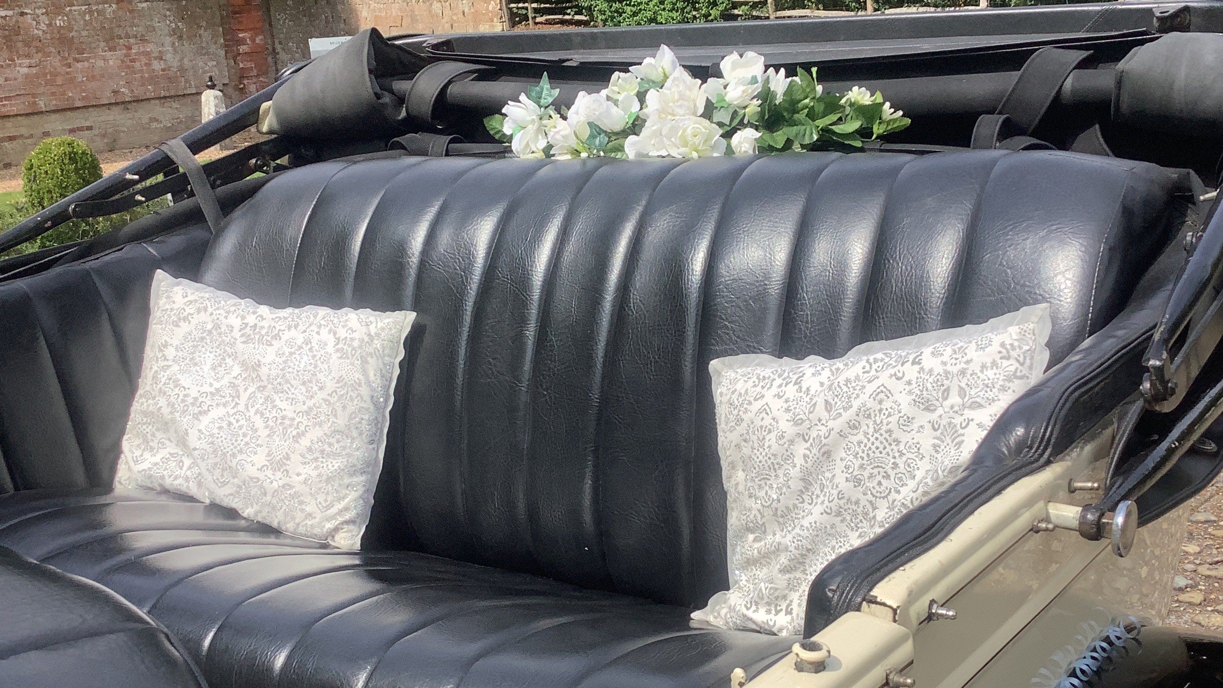 rear interior seats in black leather, white posy of flowers on the parcel shelf and cushions on the rear bench seat