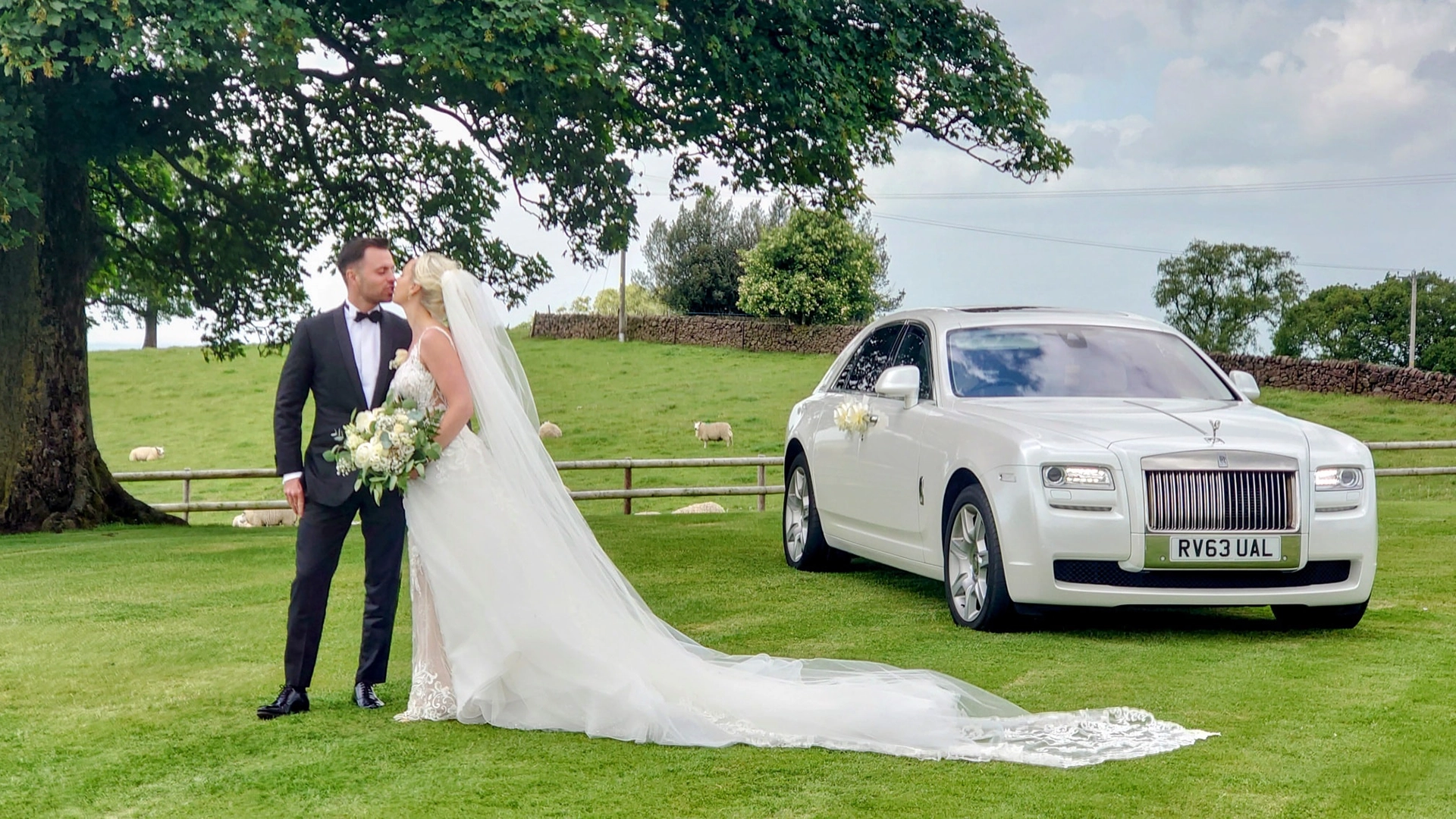 White Rolls-Royce Ghost with Bride and Groom standing by the vehicle kissing