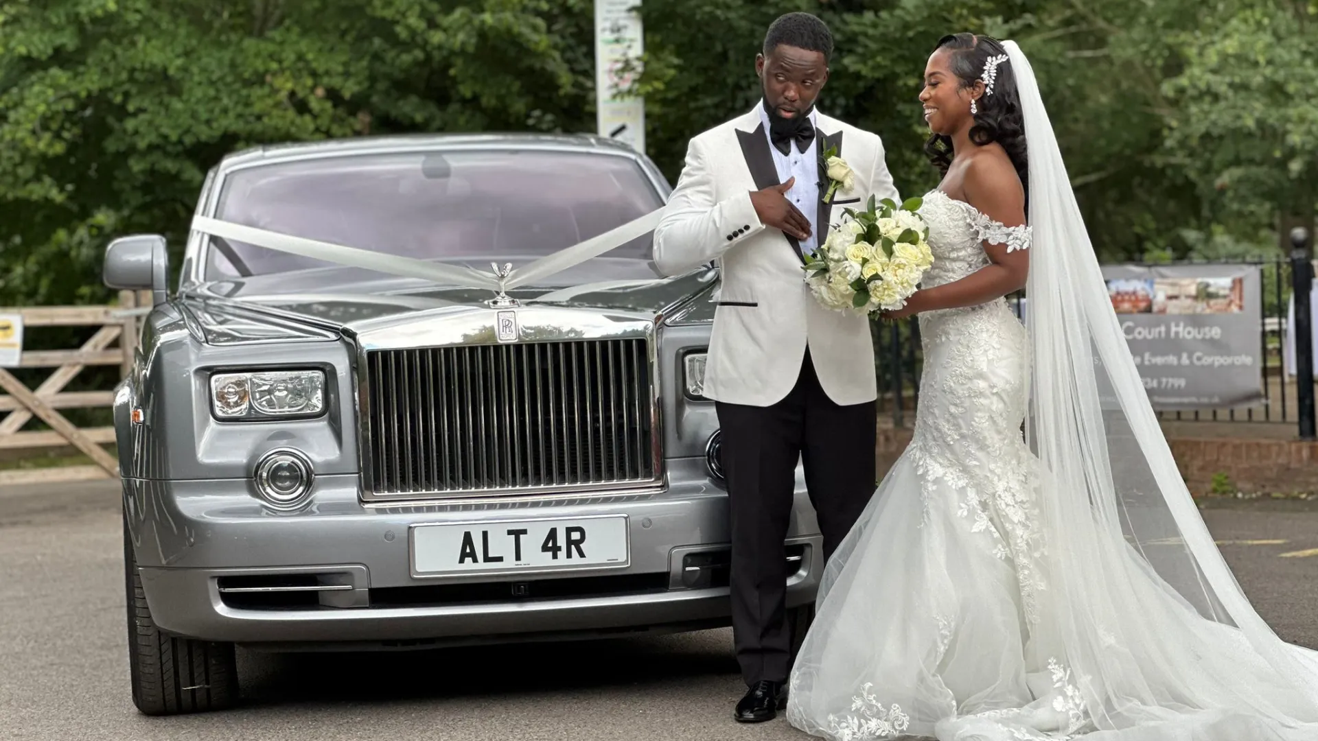 TYound newly wed couple standing on front of the silver Rolls-Royce Phantom