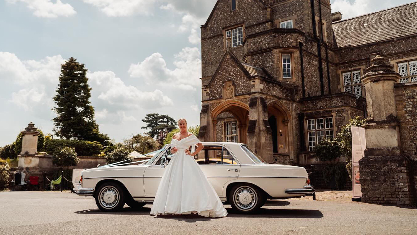 Bride wearing a white dress in front of a Classic Mercedes