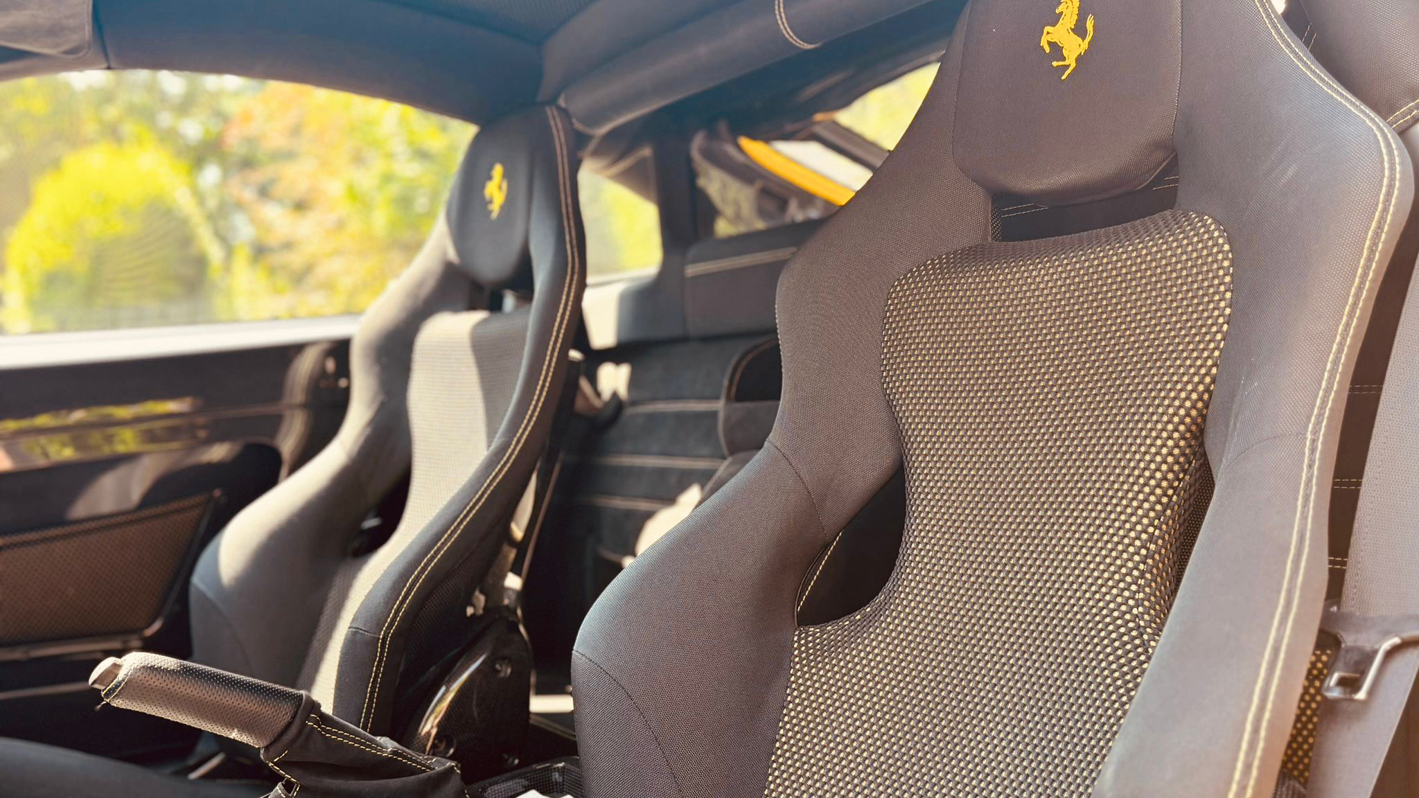 interior of Ferrari with sport bucket seats in dark grey with Yellow ferrari emblem on headrest