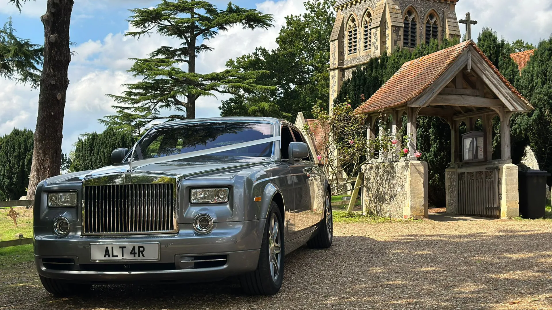 Rolls-Royce Phantom in silver with white ribbons parked in front of church