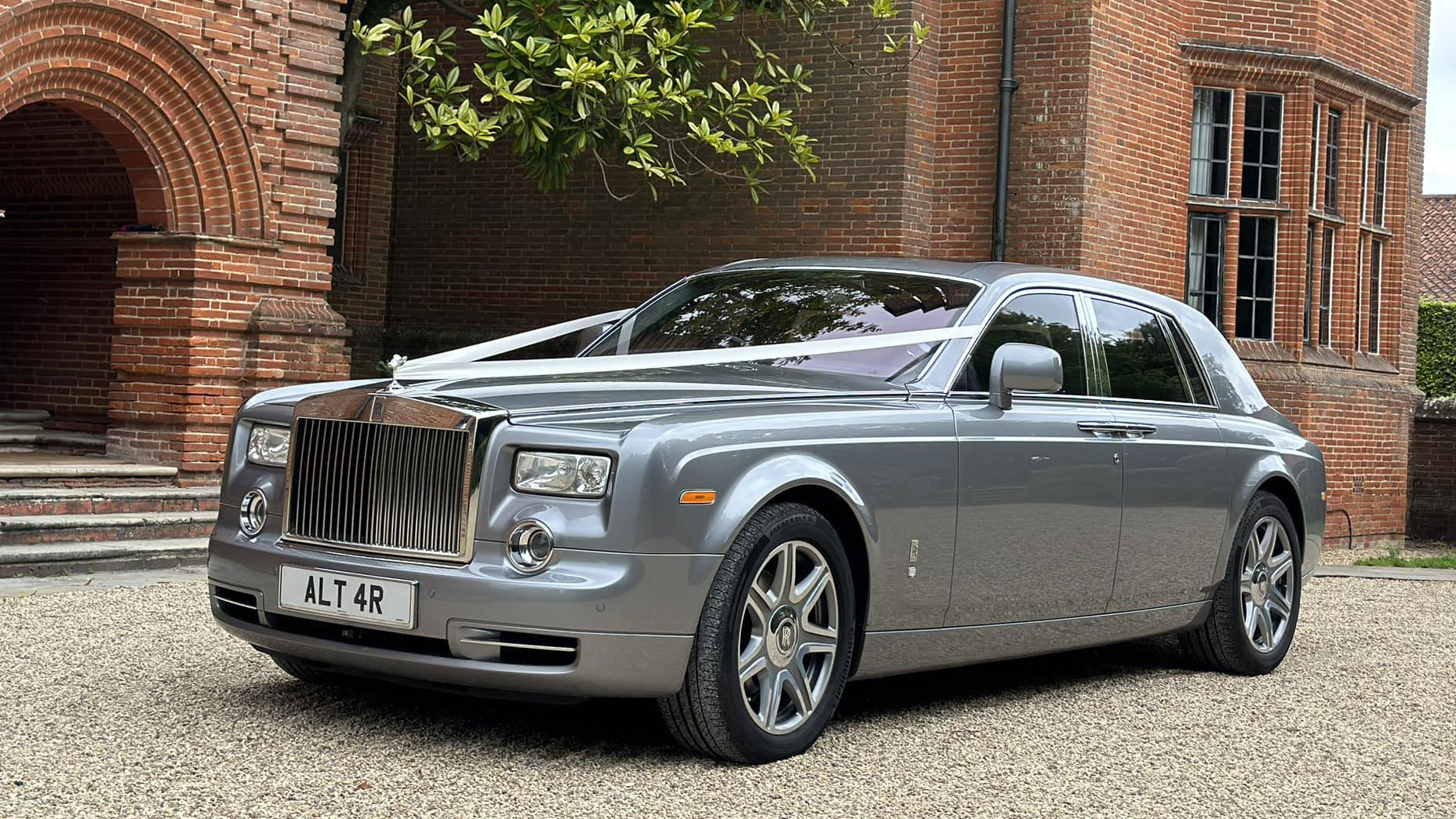 Front left view of Silver Rolls-Royce Phantom dressed with white ribbons accross the bonnet.