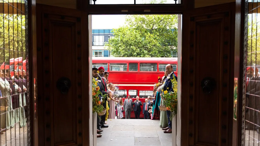 Double Decker Red Routemaster Bus parked outside London Registrar office with Wedding Guests waiting for couple to exit the venue