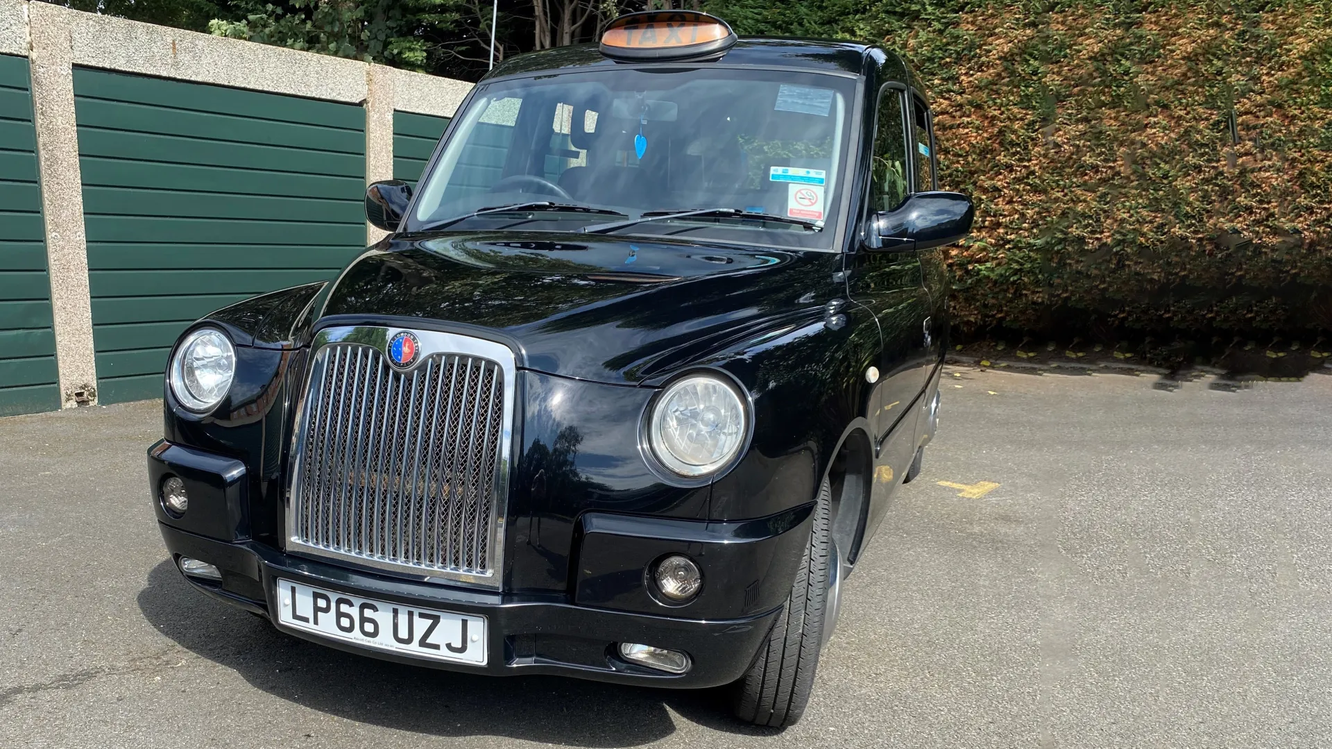 Modern Black London Taxi Cab front view with Taxi sign on roof