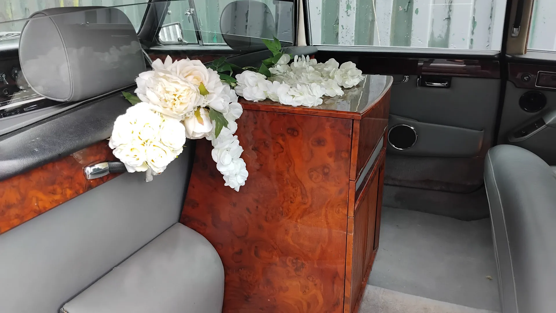 Rear interior cabin with both casual seats tucked in and white flower decoration behind front headrests and cocktail cabinet