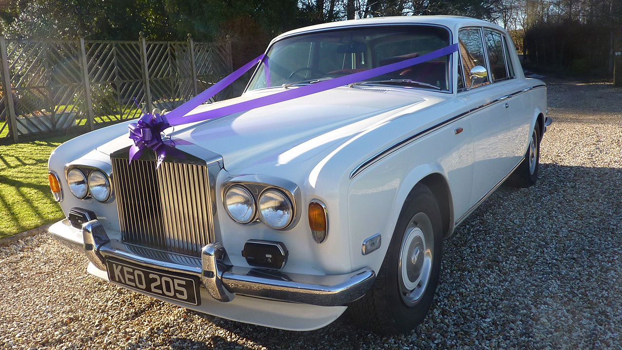 White Classic Rolls-Royce Silver Shadow mk1 with its chrome bumper decorated with Purple ribbons