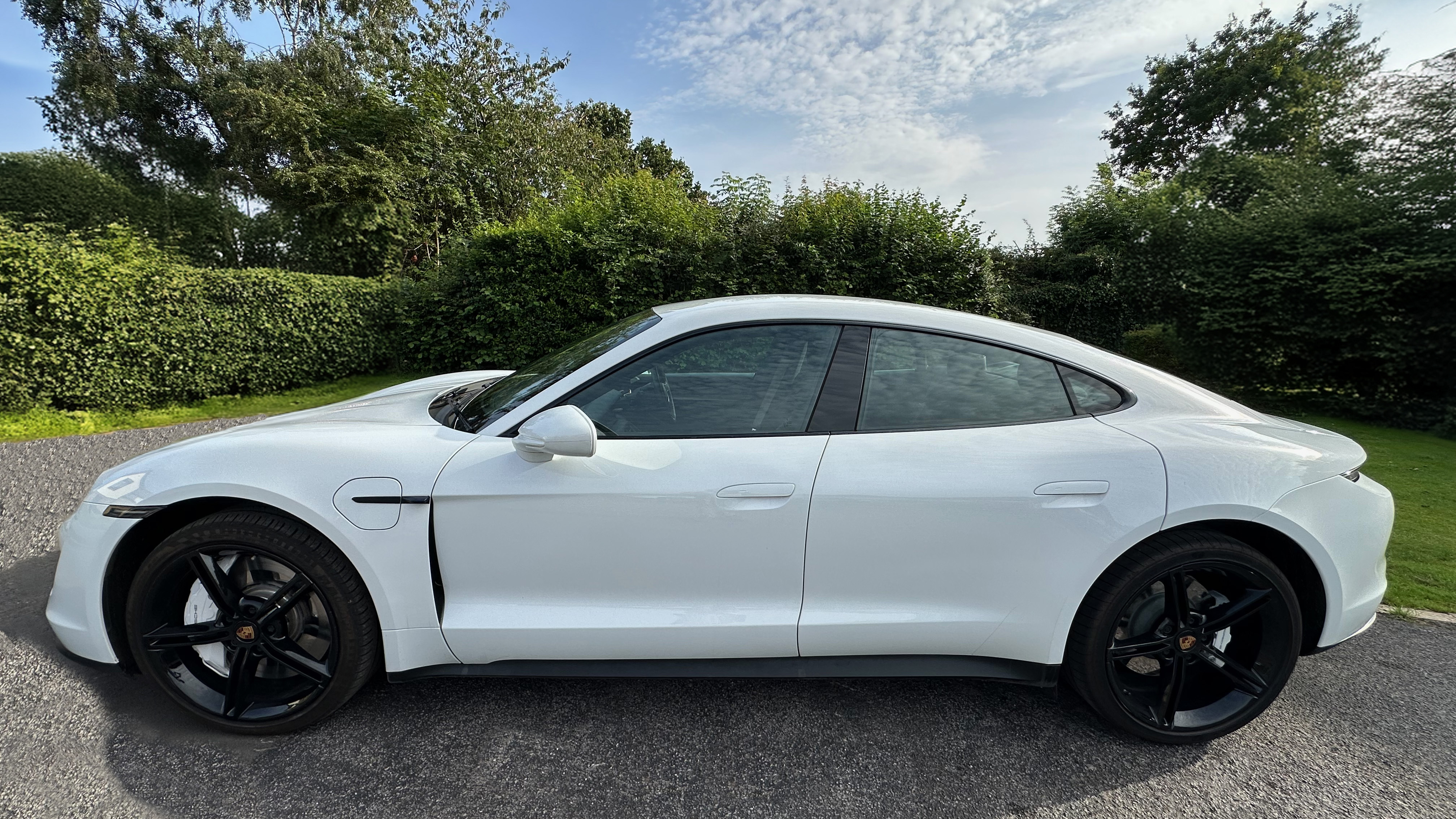 Left side view of White Porsche Taycan with black a wheels