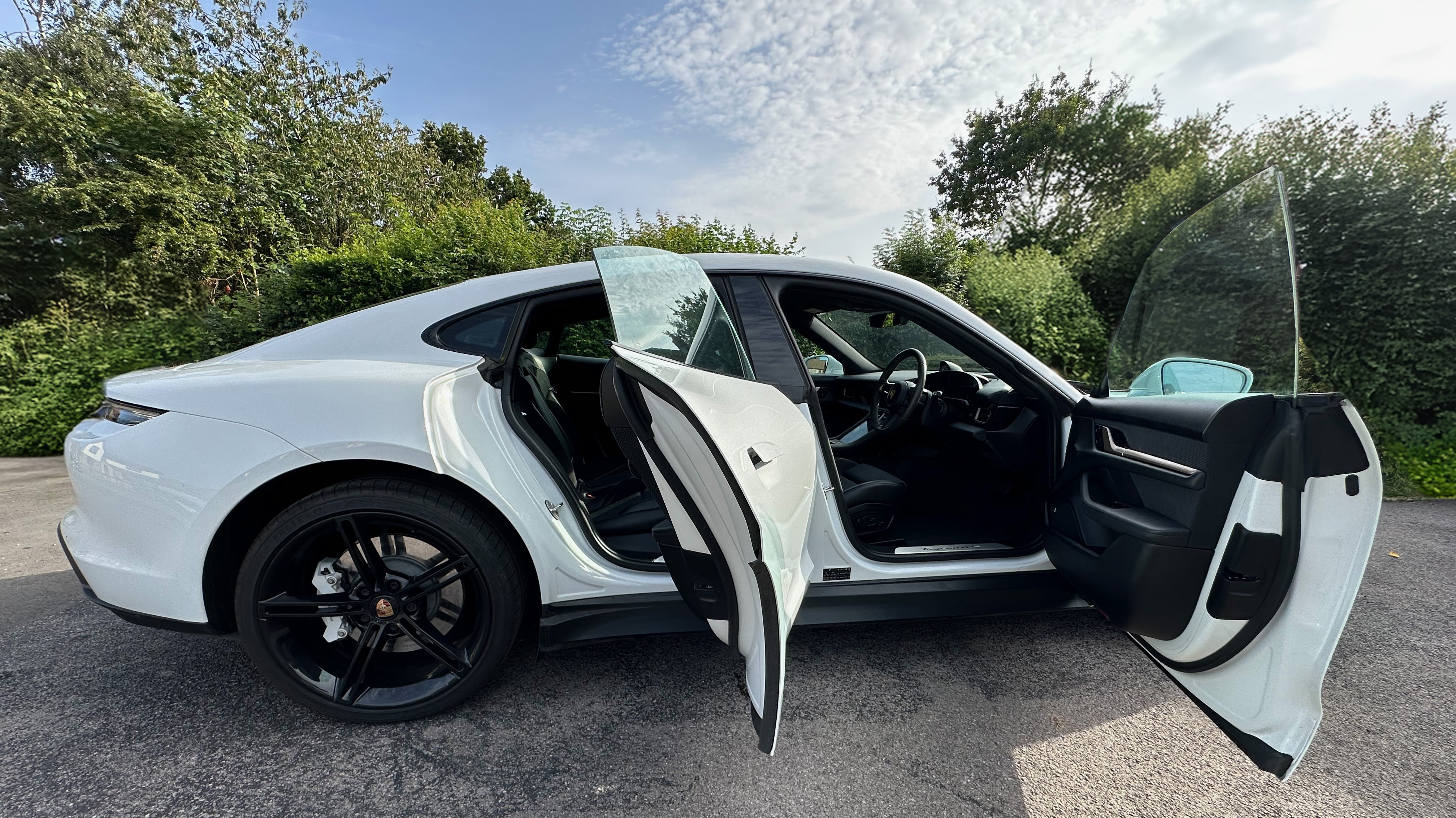 right side view of White Porsche Taycan with black a wheels and doors open