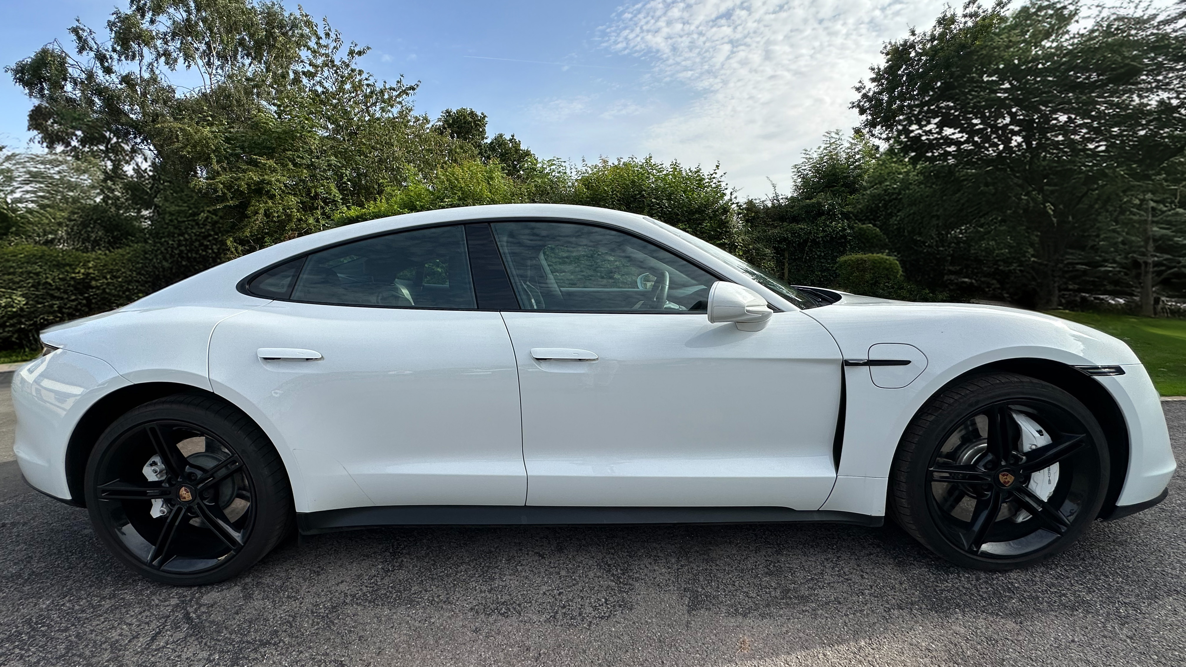 right side view of White Porsche Taycan with black a wheels