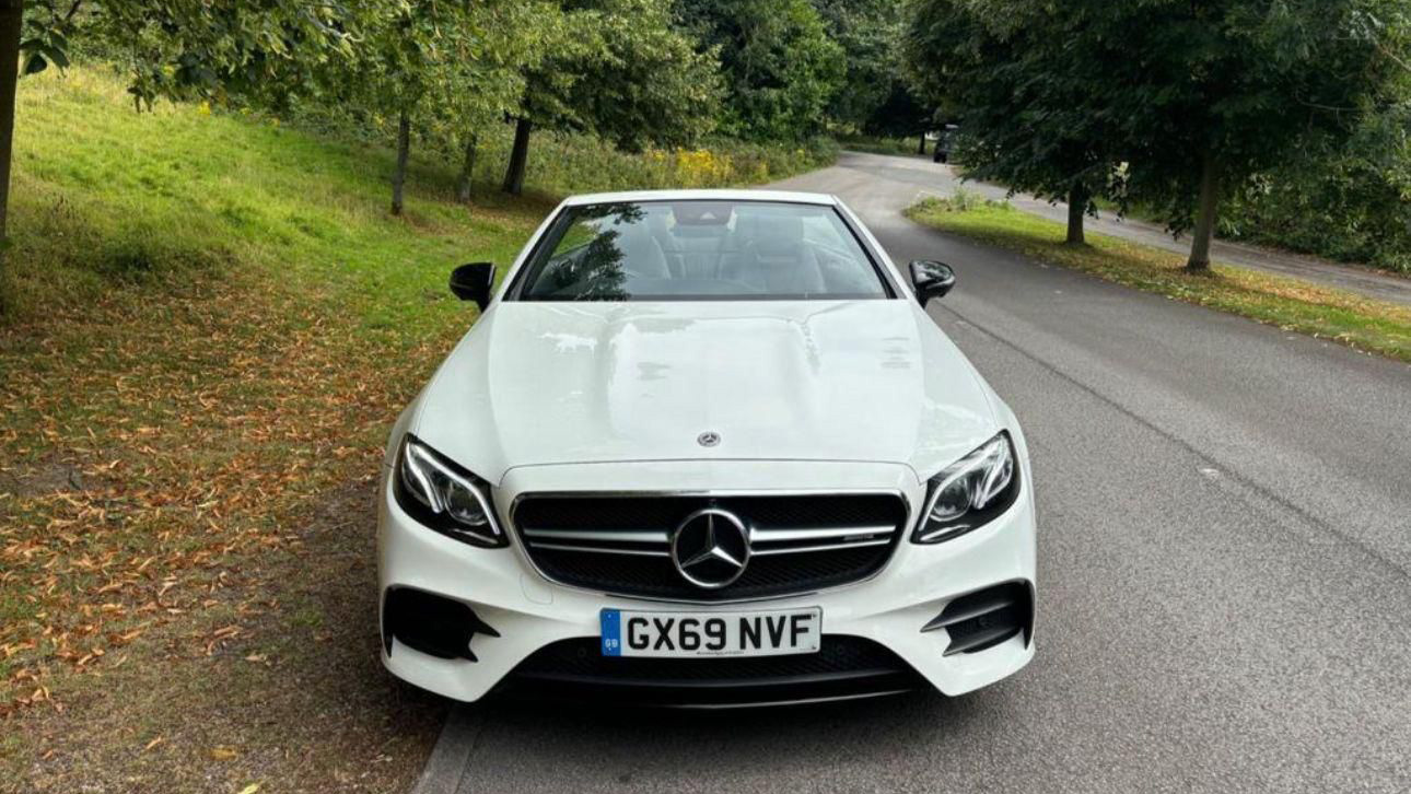 Full front of White Mercedes E-class with large Mercedes Logo on the front grill