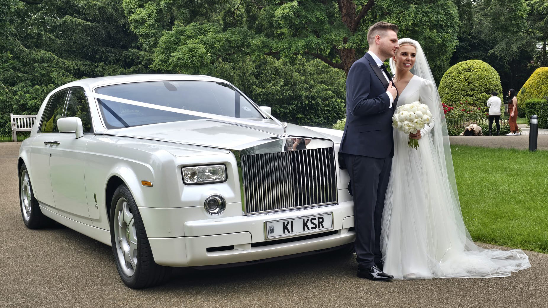 Bride and Groom in Front of a White Rolls-Royce Phantom decorated with white ribbons