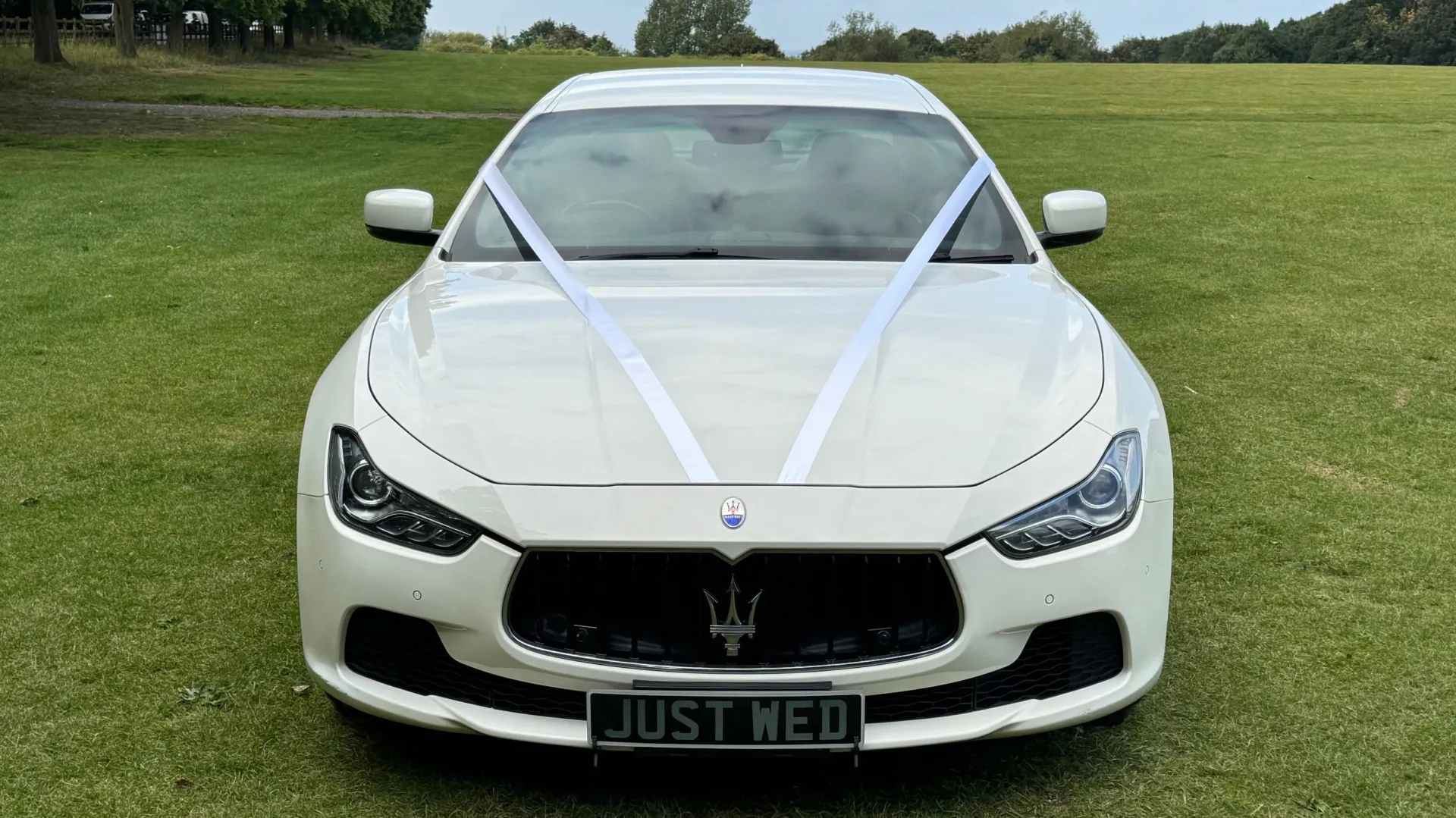 Front view of white maserati ghibli decorated with white ribbons