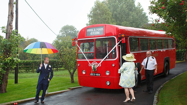 Vintage single decker bus at a wedding with wedding guests standing around the bus