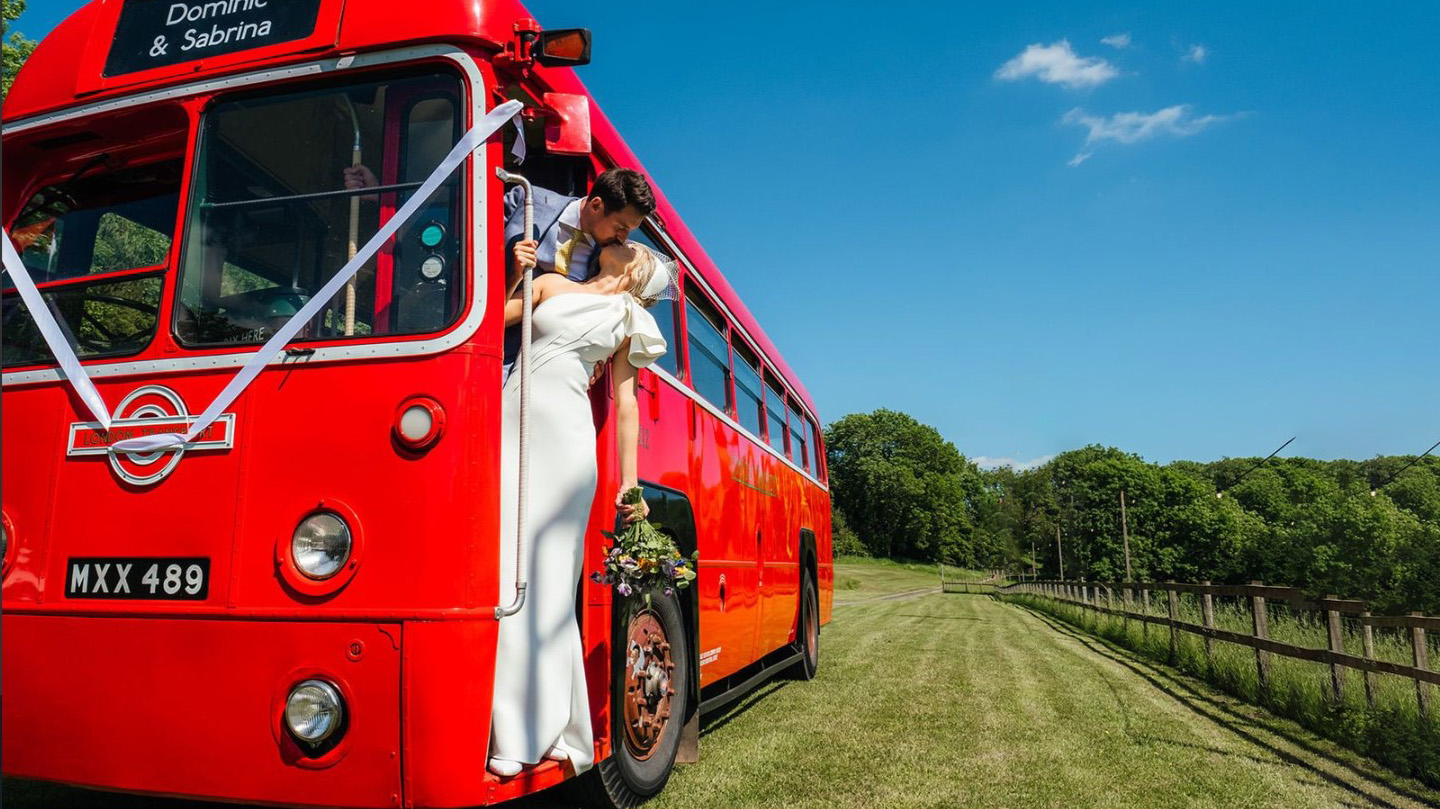 Bride and Groom kissing on the door step of a vintage red bus