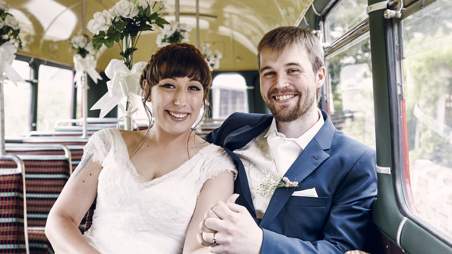 Bride and groom smiling sat inside a vintage Single decker us