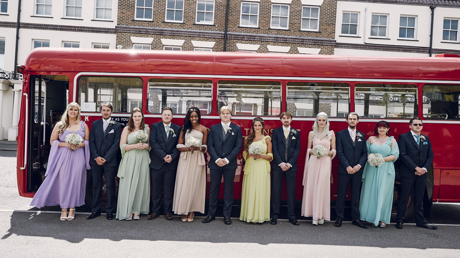 Wedding Guests lined up in front of Single Decker Classic Red bus