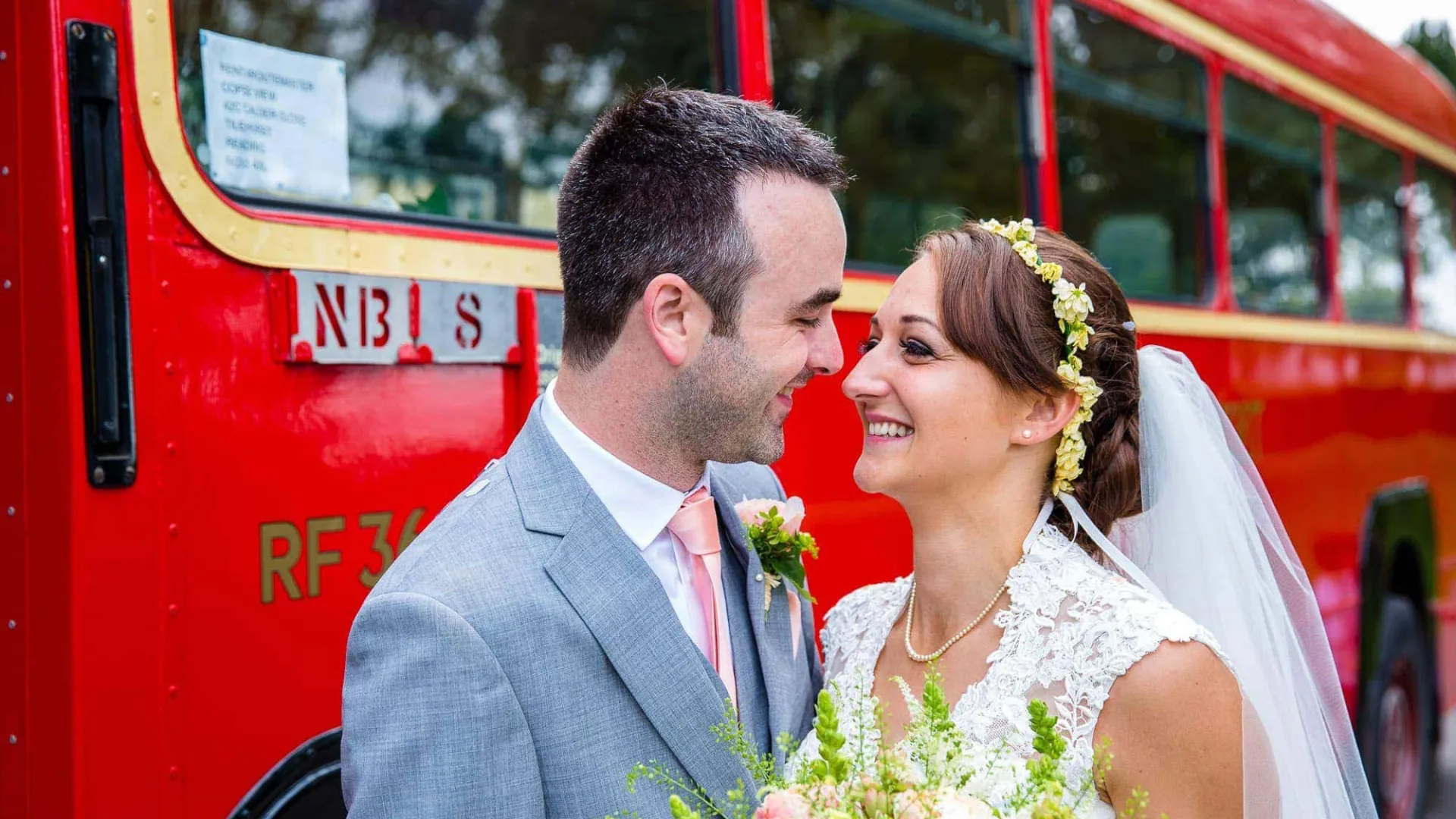 Bride and Groom smiling at each other's in front of red single decker bus