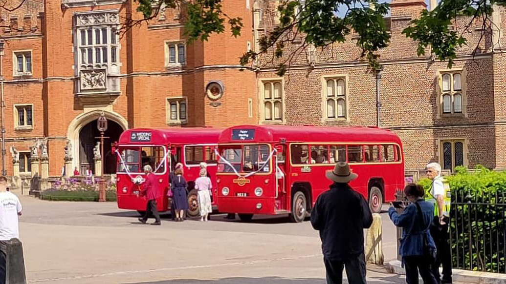 two singe decker red bus in front of wedding venue