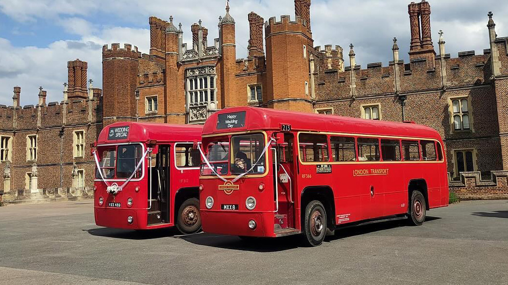 Two identical Single Decker red Routemaster buses parked next to each others in front of wedding venue