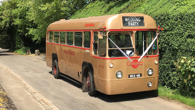 Right Front view of Gold Classic dingle decker wedding bus with white ribbons