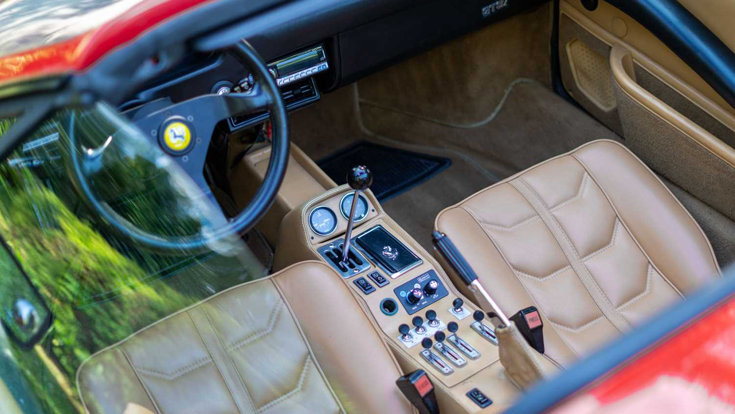 Aerial view of tan leather interior of Red Ferrari taken through the open roof