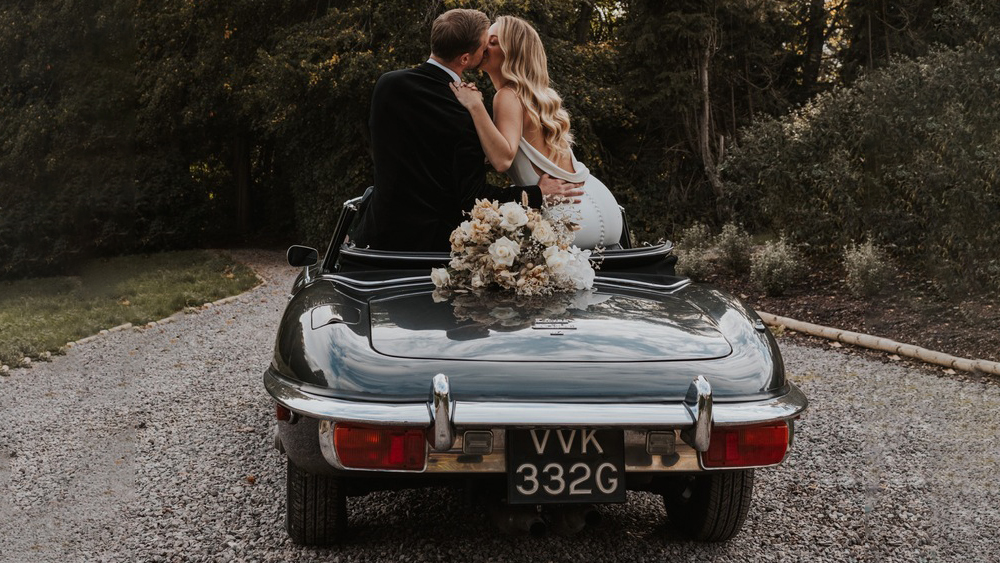 Bride and Groom kissing inside the Convertible Jaguar e-type