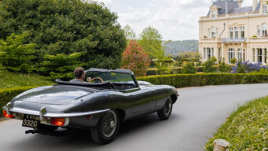 rear view of classic jaguar e-type with convertible roof down entering wedding venue