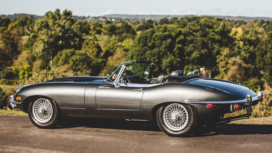 Left side view of gun metal grey Jaguar E-type with soft-top roof down