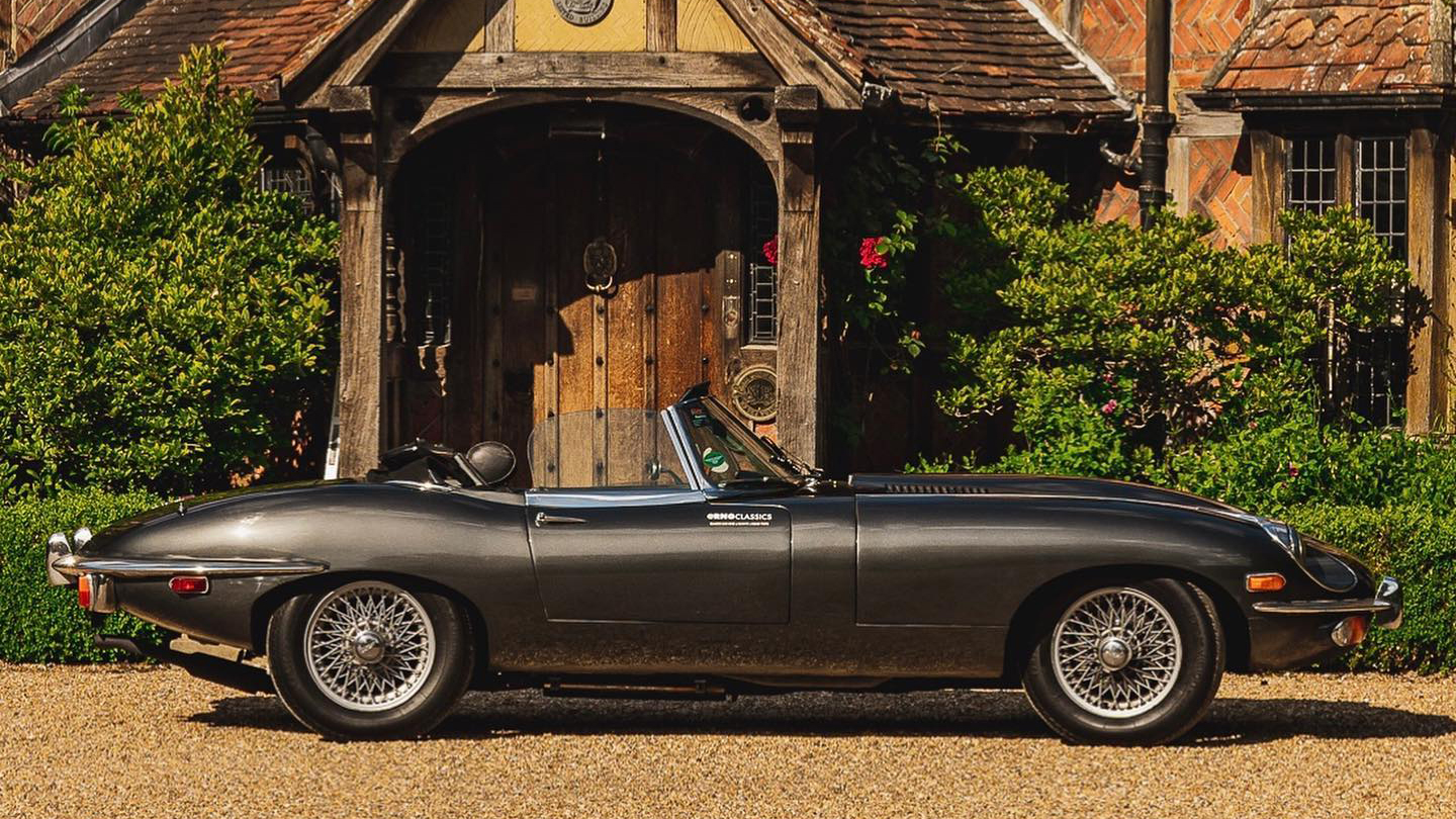 right side view of convertible classic jaguar e-type with roof down parked in front of wedding venue in Surrey