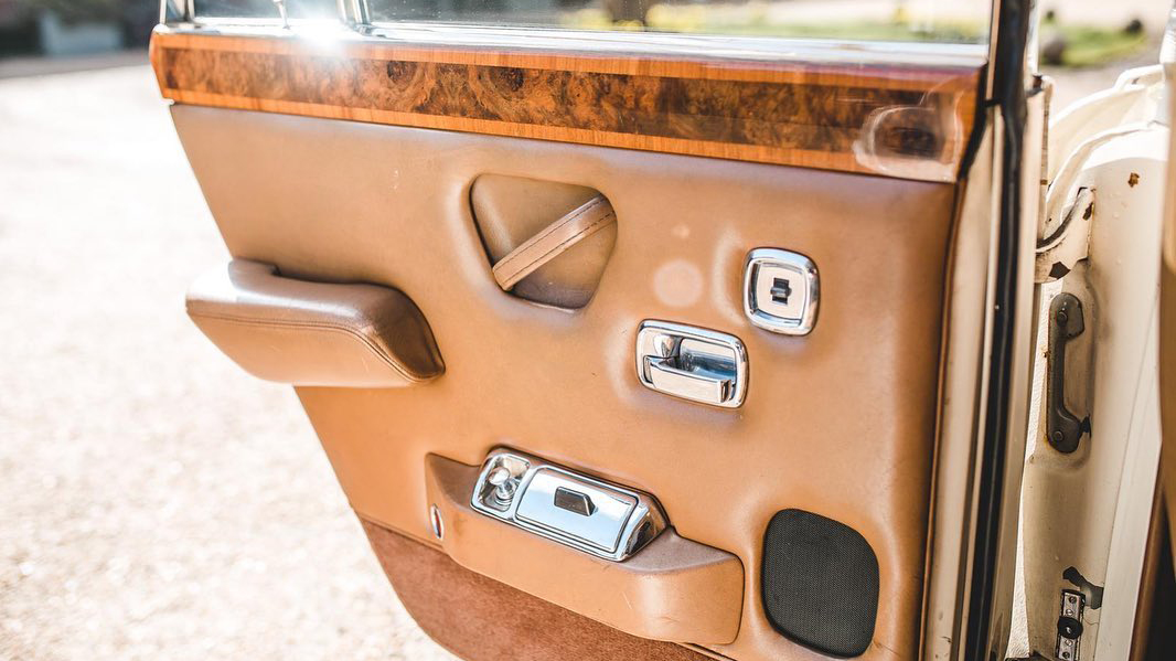 Inside door card in Classic 70s Rolls-Royce with cream leather door cards and wooden panel on top of the door