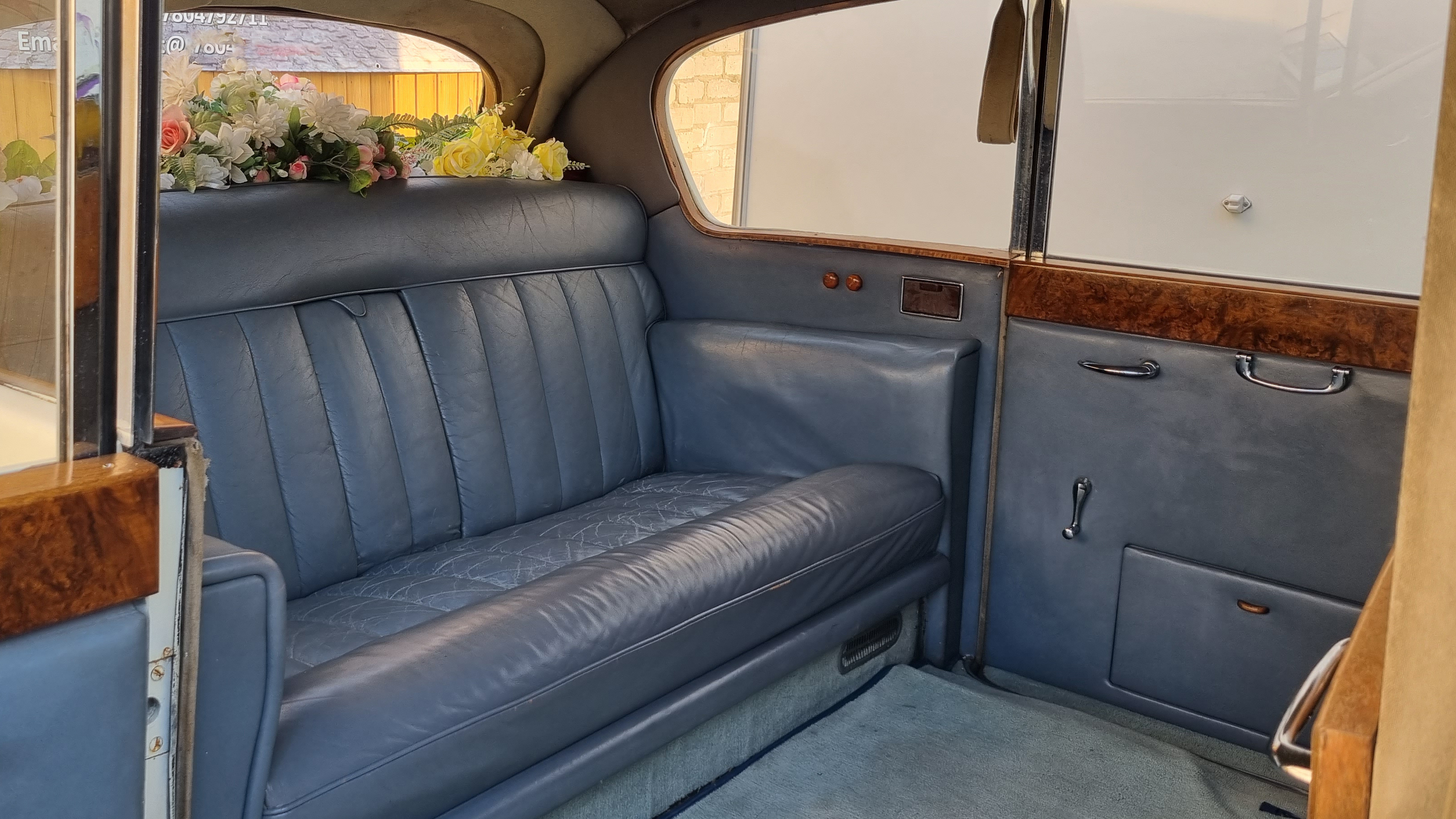 rear interior space inside Austin Princess Limousine with casual seats retracted. Silver leather interior and wood features on top of the doors