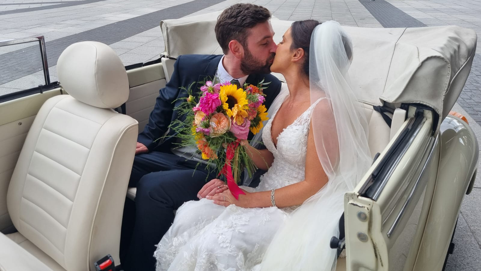 Bride and Groom kssing inside a classic vw beetle with white leather seats