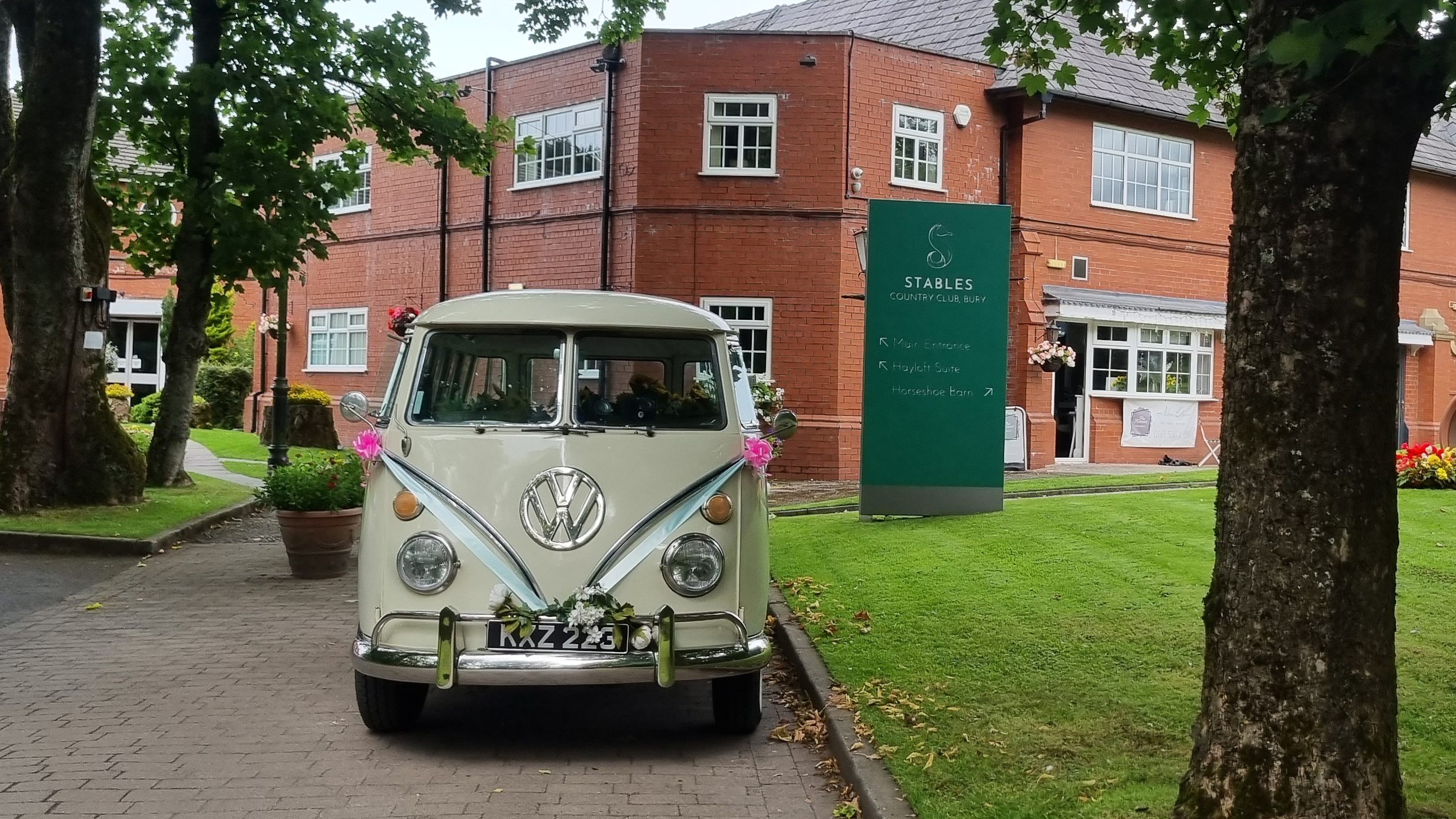 Front view of a Classic VW Campervan with blue ribbons and pink bows in front of a venue in Lancashire