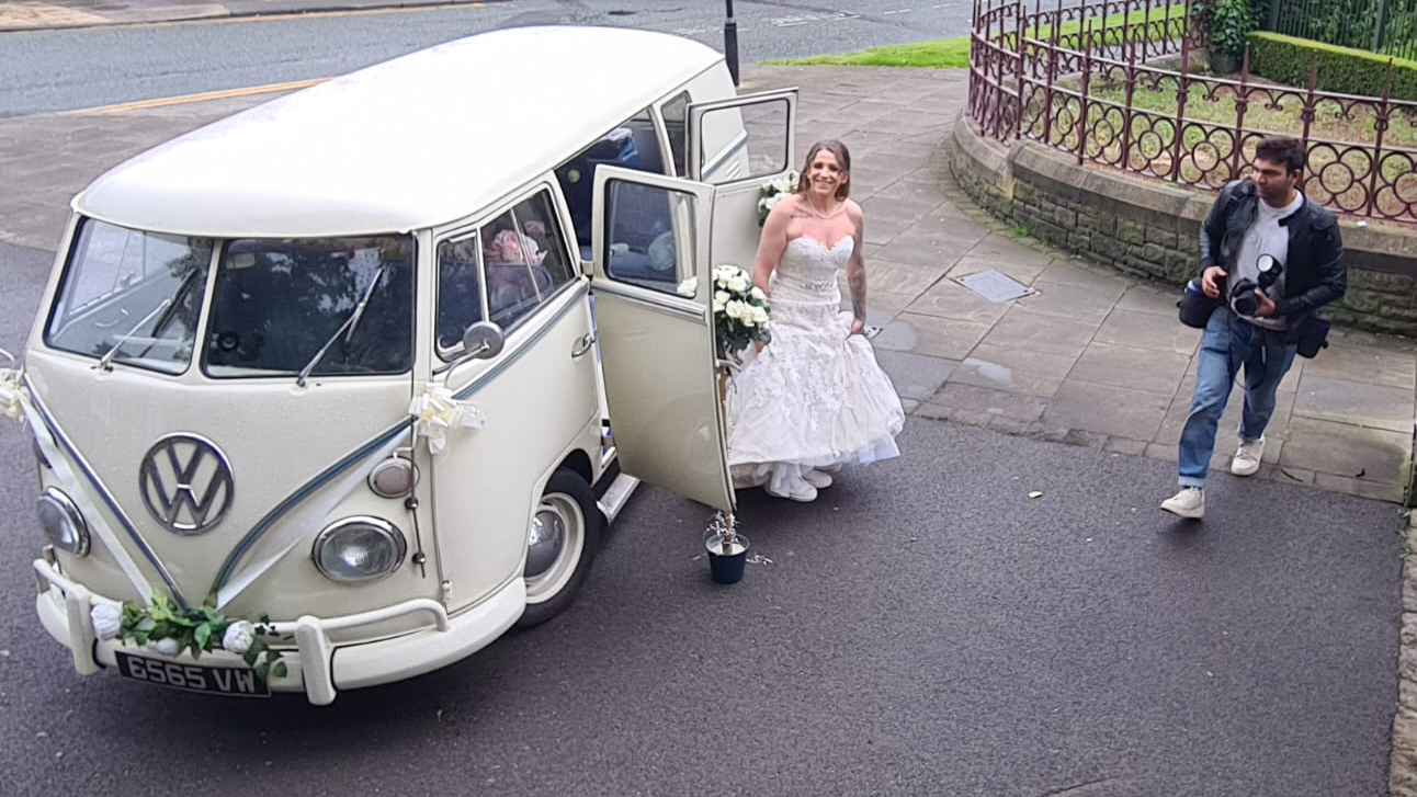 Aerial view of Bride exiting a classic vw campervan in her wedding dress