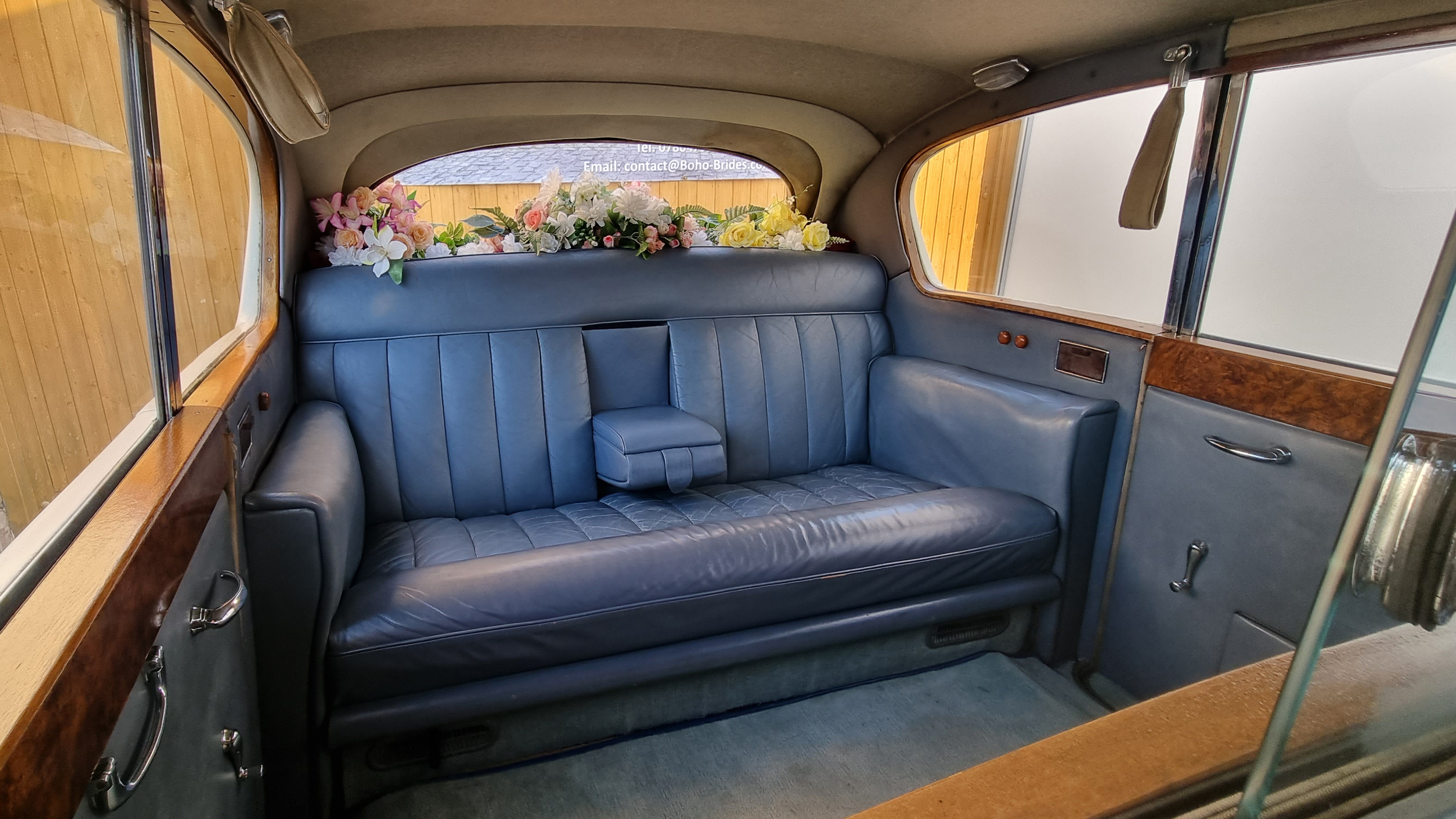 rear interior space inside Austin Princess Limousine with casual seats retracted. Silver leather interior and wood features on top of the doors