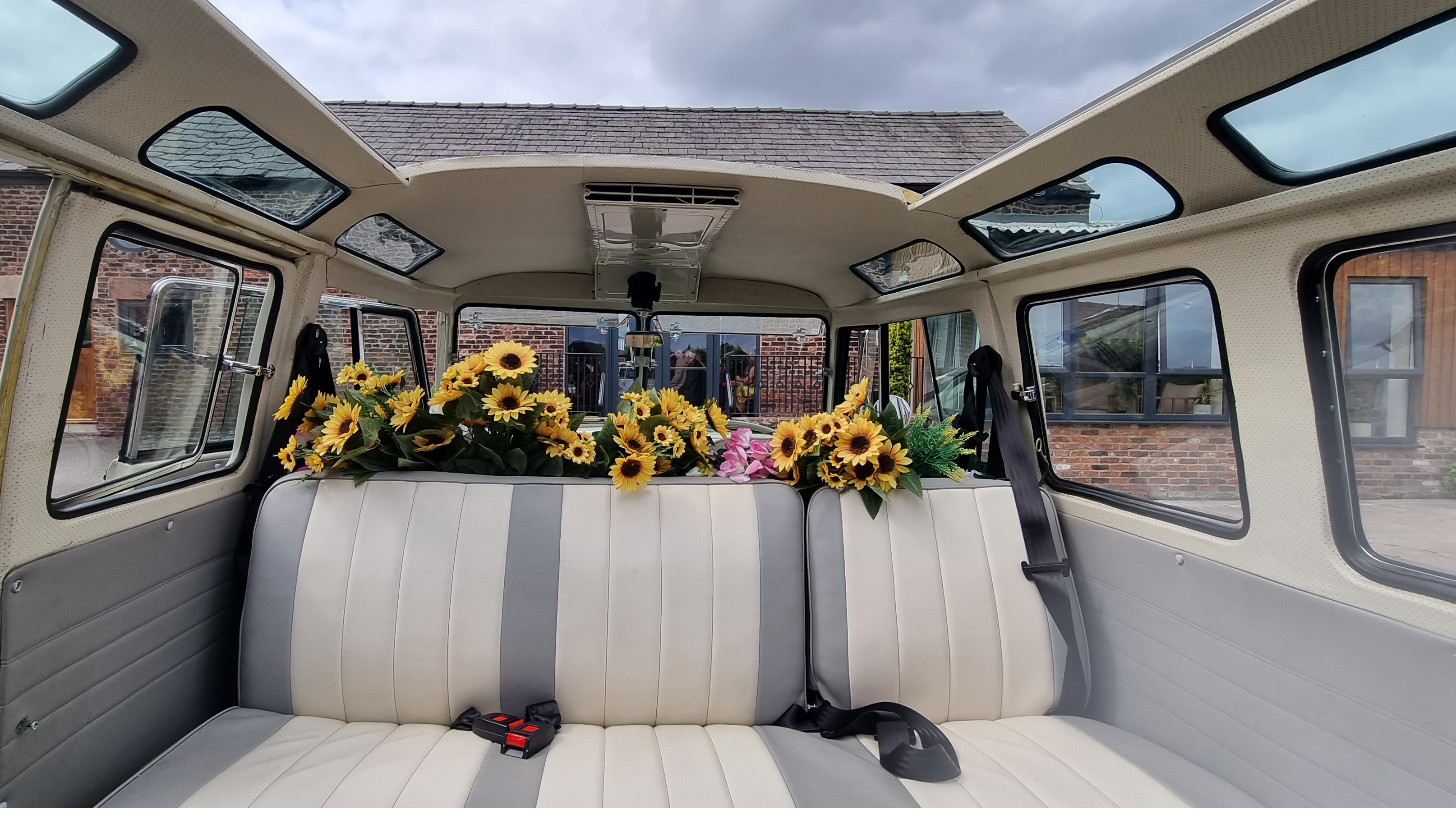 Classic VW campervan interior in Cream and silver decorated with yellow sunflowers and large panoramic sunroof open