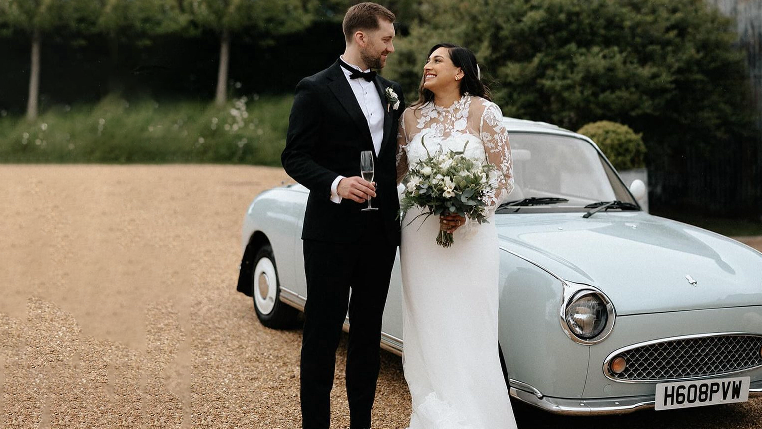 Bride and Groom standing in front of Classic Nissan Figaro in light blue