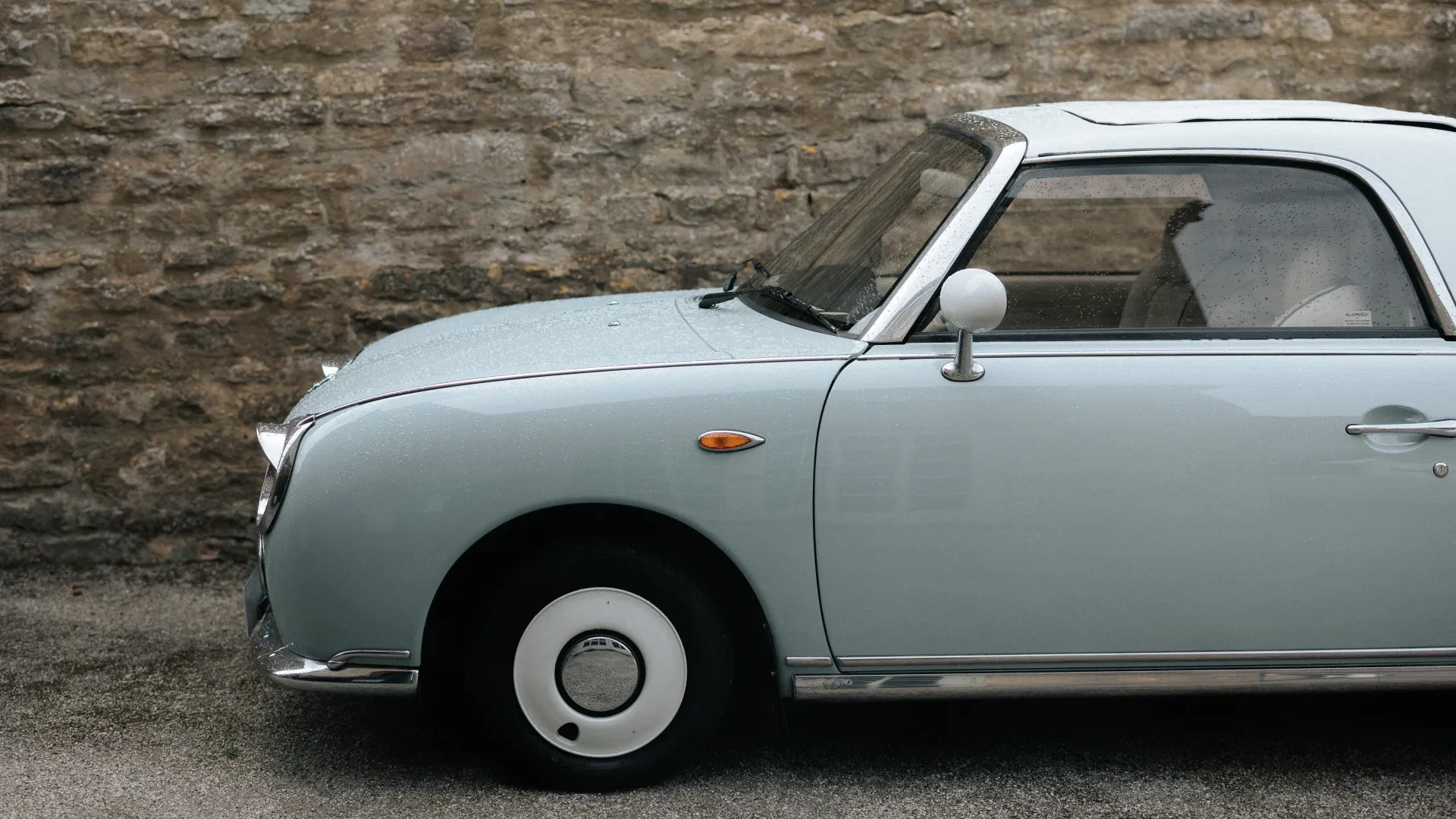 side front view of Classic Nissan Figaro with light blue, white wheel caps and white roof