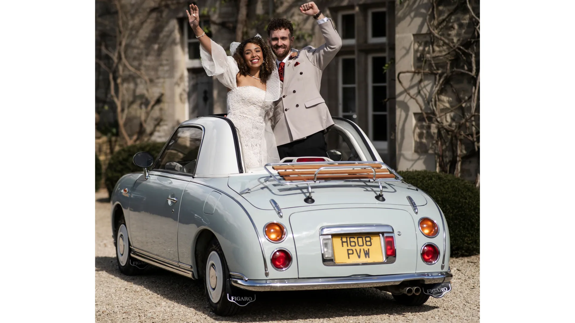 Newly married couple standing inside a Nissan Figaro through the open roof