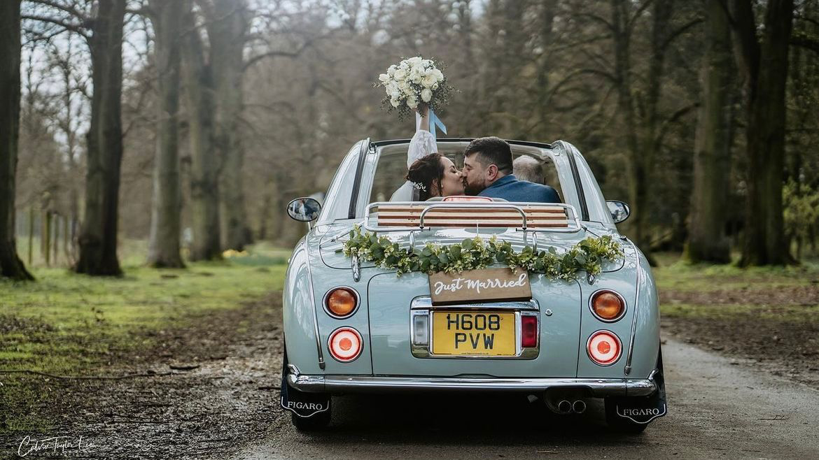 Bride and Groom kissing inside a Classic Nissan Figaro with roof down