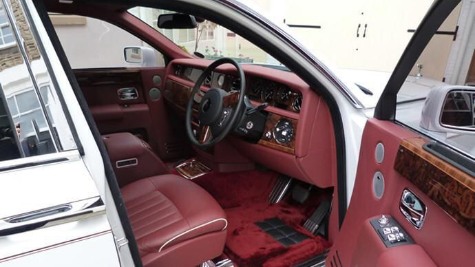 Front driver seat of Rolls-Royce Phantom with Burgundy leather, matching burgundy dashboard and Burgundy carpet.