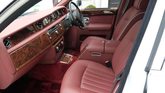 Front passenger seat inside Rolls-Royce Phantom with Burgundy leather seat, wooden dash surrounded by Burgundy leather