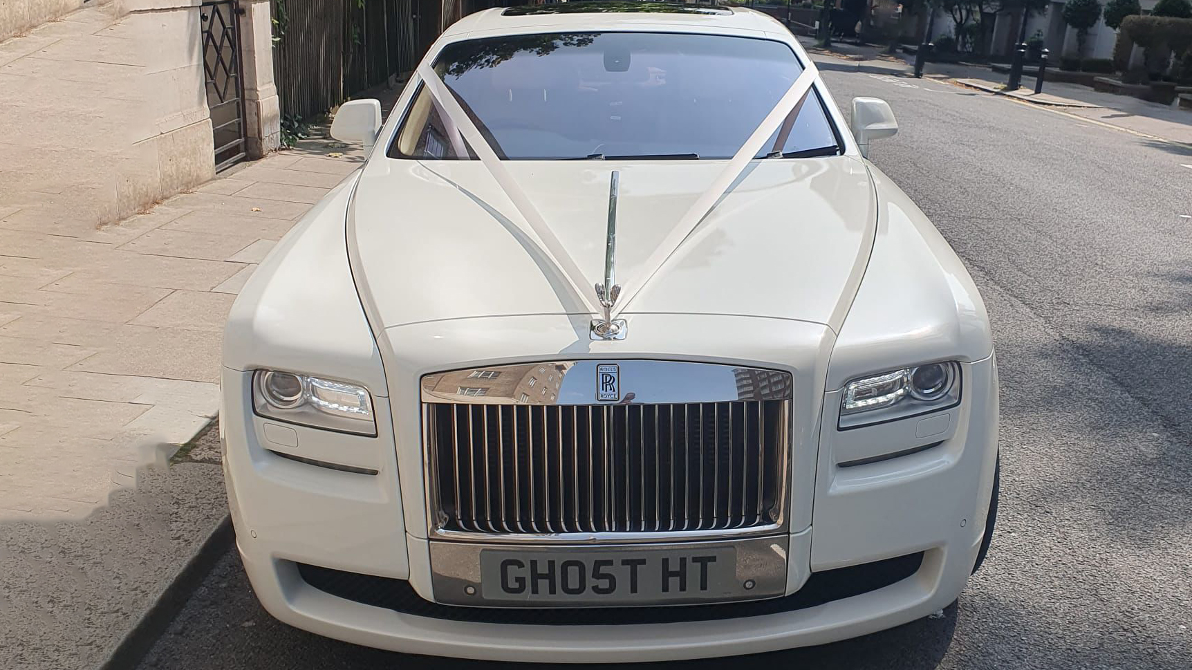 Full front view of White rolls-Royce Ghost with white bonnet and decorated with white ribbons