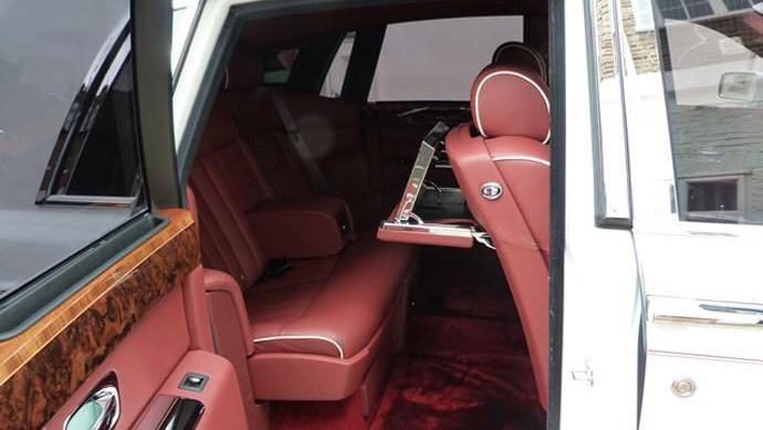 Rear interior seating of Burgundy Leather and wooden panels on top of the door