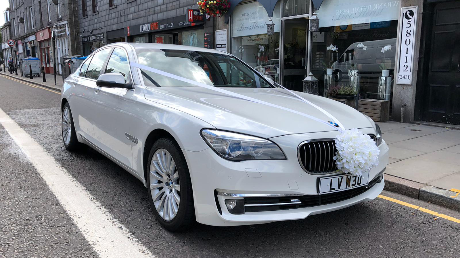 White BMW with white ribbons and bow parked in the street of Aberdeen