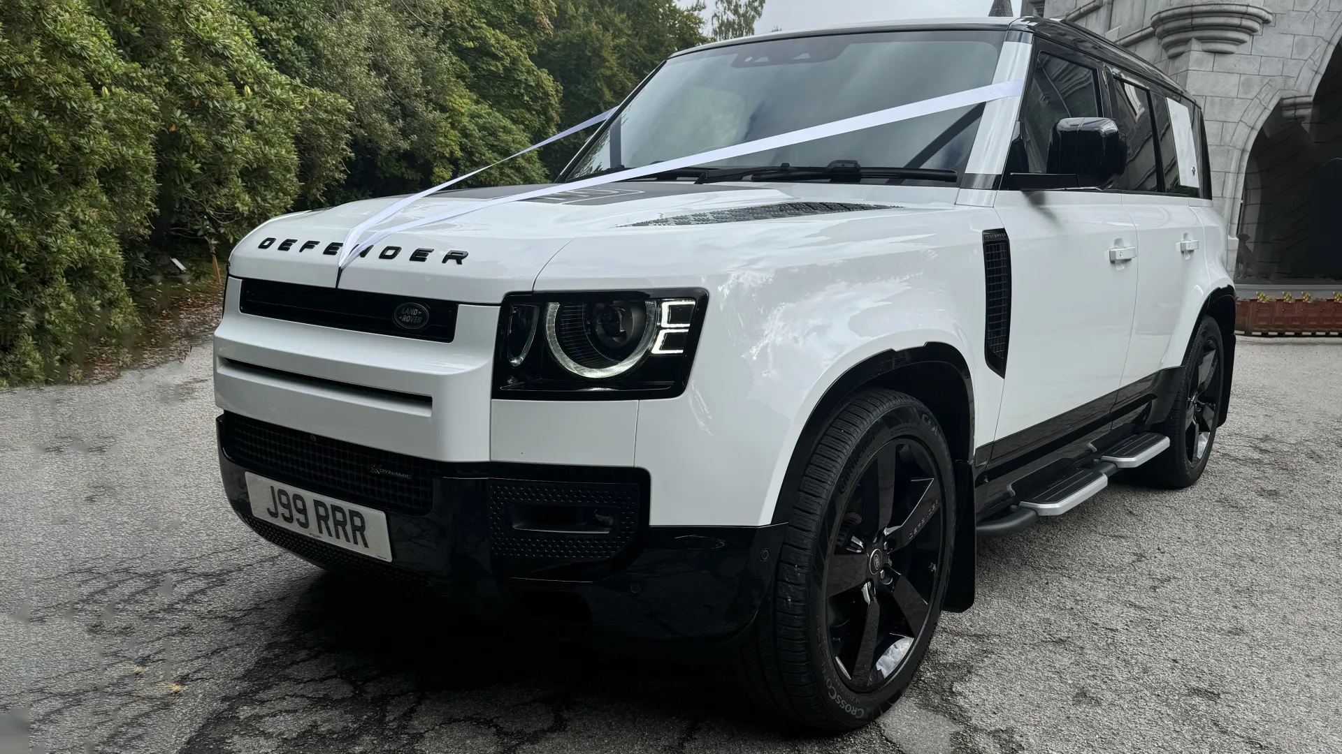 White Land Rover Defender with black alloy wheels decorated with White Ribbons