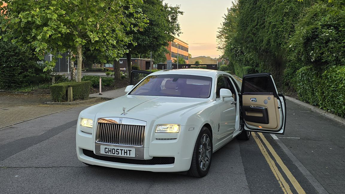 white Rolls-Royce Ghost parked in the Street of London with forward facing rear door open showing Cream and Mocha Leather Interior