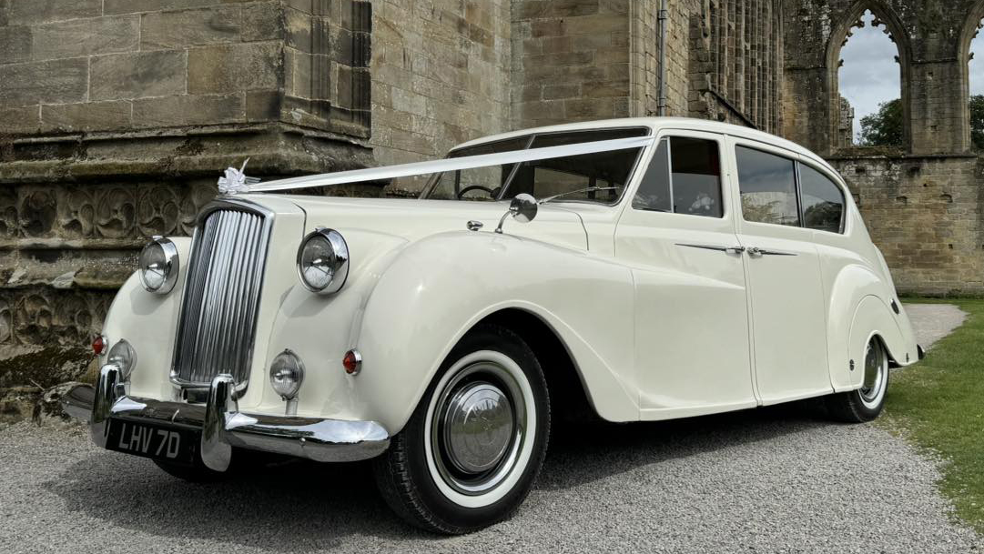 Front left view of classic Austin Princess limousine dressed with Ivory ribbons