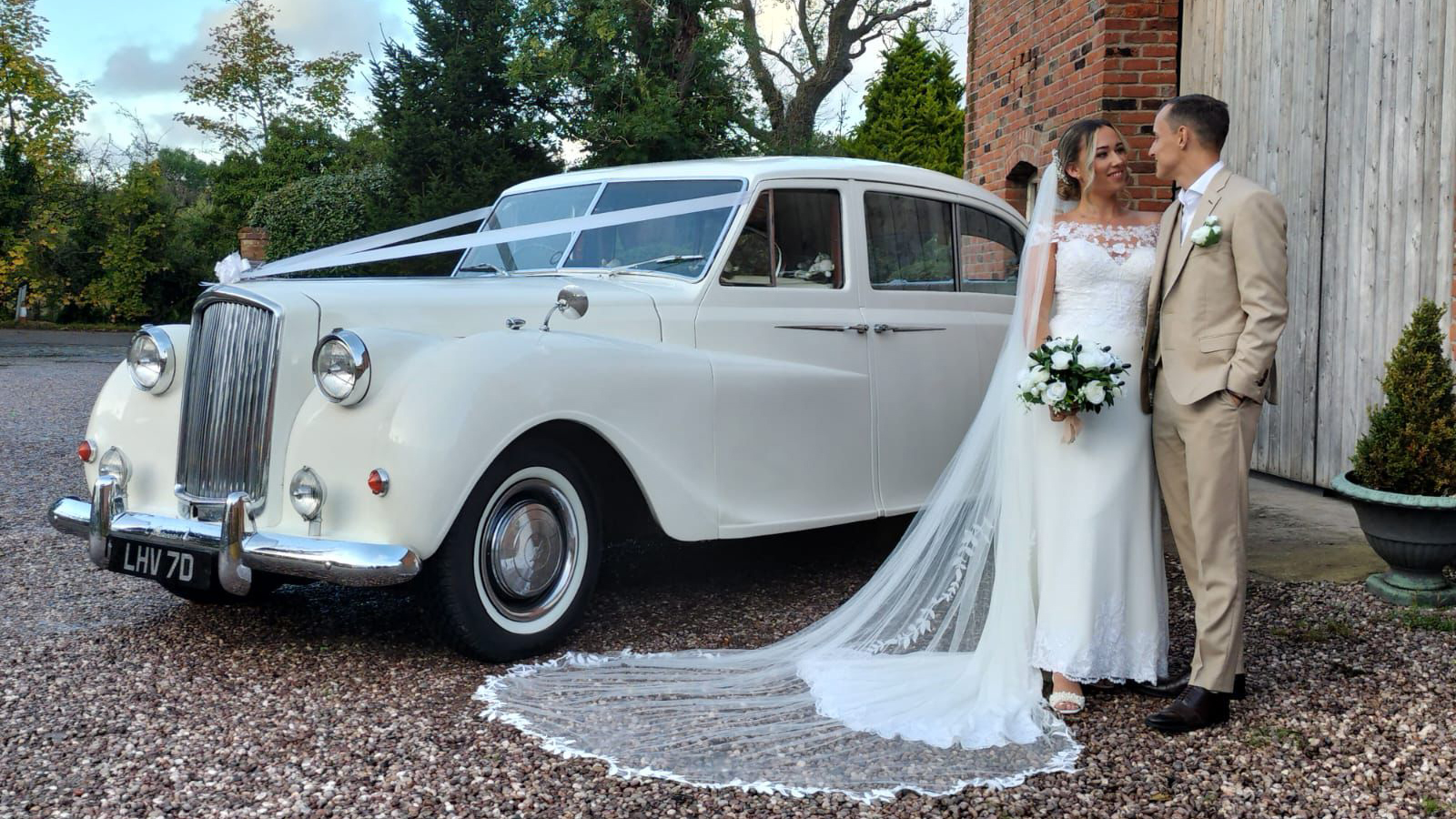 Classic Austin Princess Limousine in White with Bride and Groom standing next to the vehicle